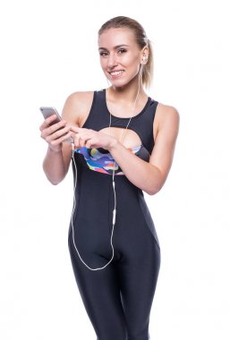 Kulaklık ile spor giyim eşofman giyen mutlu fitness genç kadın bir smartphone kullanarak müzik dinleme.