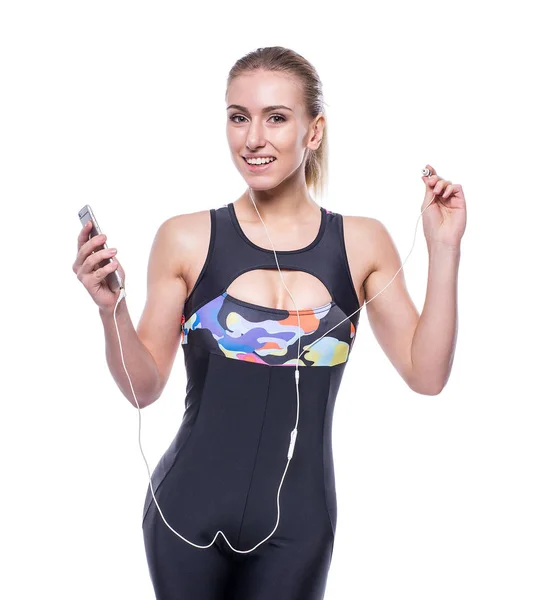 Felice fitness giovane donna che indossa tuta sportiva con auricolari sta ascoltando la musica utilizzando uno smartphone . — Foto Stock