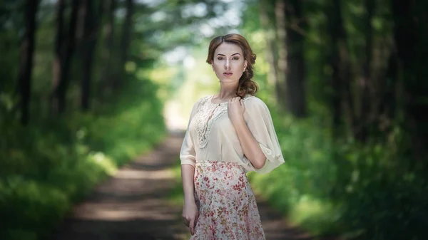 Портрет красивої молодої жінки, що йде в казковому лісі з букетом квітів . — стокове фото