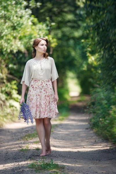 Portret van mooie jonge vrouw lopen in een forest fairy met boeket bloemen. — Stockfoto