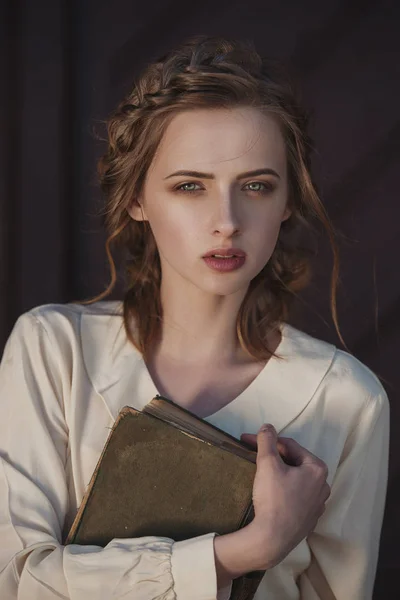 Retro portret van een prachtige dromerig meisje bedrijf een boek in handen buitenshuis. Zachte vintage toning. — Stockfoto