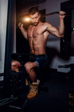 Kaslı vücut geliştirmeci yakışıklı erkekler çıplak gövde ile spor salonunda egzersiz yapıyor. Karın kasları ve pazı ile güçlü atletik bir adam.