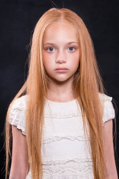Крупный план портрета милой маленькой девочки с рыжими волосами в студии на темном фоне . — стоковое фото