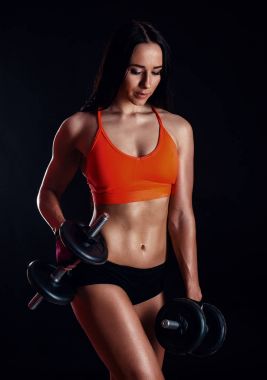 Güzel seksi kız siyah arka plan üzerinde izole dumbbells ile egzersiz yapıyor. Atletik genç kadın ne ağırlıkları ile bir fitness egzersiz.