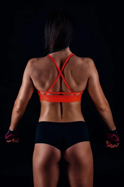 Beautiful fitness sexy slim female in activewear posing over black background. Back view. — Stock Photo, Image