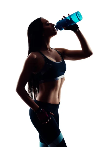 Attraente giovane donna sportiva che beve dalla bottiglia blu shaker in studio. Foto di silhouette. Isolato su sfondo bianco . — Foto Stock