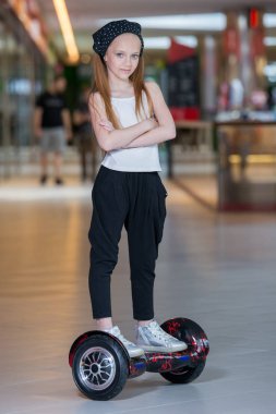 Alışveriş Merkezi Ticaret mini segway üzerinde mutlu ve gülümseyen Kız biniyor. Vurgulu kurulu veya gyroscooter üzerinde sürme genç.