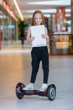 Alışveriş Merkezi Ticaret mini segway üzerinde mutlu ve gülümseyen Kız biniyor. Vurgulu kurulu veya gyroscooter üzerinde sürme ve boş sayfa tutan genç.