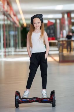 Alışveriş Merkezi Ticaret mini segway üzerinde mutlu ve gülümseyen Kız biniyor. Vurgulu kurulu veya gyroscooter üzerinde sürme genç.