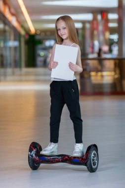 Alışveriş Merkezi Ticaret mini segway üzerinde mutlu ve gülümseyen Kız biniyor. Vurgulu kurulu veya gyroscooter üzerinde sürme ve boş sayfa tutan genç.