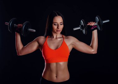 Güzel seksi kız siyah arka plan üzerinde izole dumbbells ile egzersiz yapıyor. Atletik genç kadın ne ağırlıkları ile bir fitness egzersiz.