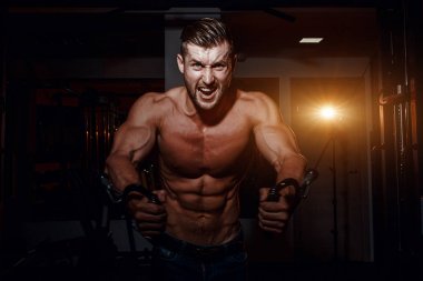 Kaslı vücut geliştirmeci yakışıklı erkekler çıplak gövde ile spor salonunda egzersiz yapıyor. Karın kasları ve pazı ile güçlü atletik bir adam.