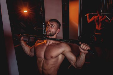 Kaslı vücut geliştirmeci yakışıklı erkekler çıplak gövde ile spor salonunda egzersiz yapıyor. Karın kasları ve pazı ile güçlü atletik bir adam.