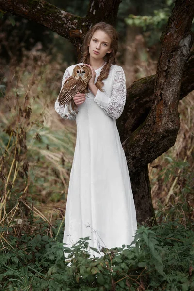 Mooie romantische vrouw met een uil. De vogel zit op haar hand. — Stockfoto