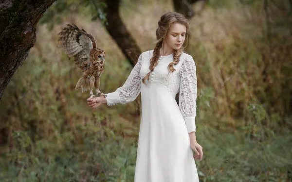 Mooie romantische vrouw met een uil. De vogel zit op haar hand. — Stockfoto