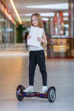 Alışveriş Merkezi Ticaret mini segway üzerinde mutlu ve gülümseyen Kız biniyor. Vurgulu kurulu veya gyroscooter üzerinde sürme ve boş sayfa tutan genç.