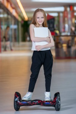 Alışveriş Merkezi Ticaret mini segway üzerinde mutlu ve gülümseyen Kız biniyor. Vurgulu kurulu veya gyroscooter üzerinde sürme ve boş sayfa tutan genç.