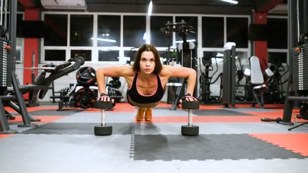 Atleta chica en ropa deportiva haciendo ejercicio y entrenando sus brazos y hombros en el gimnasio . — Vídeos de Stock