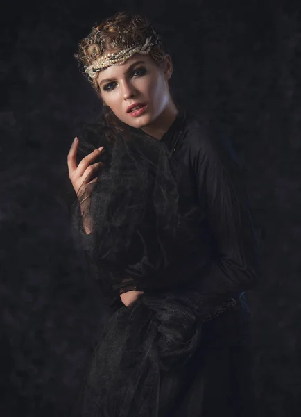 Karanlık Gotik arka plan üzerinde siyah fantezi kostüm karanlıkta kraliçesi. Yüksek moda güzellik modeli koyu makyaj ile.