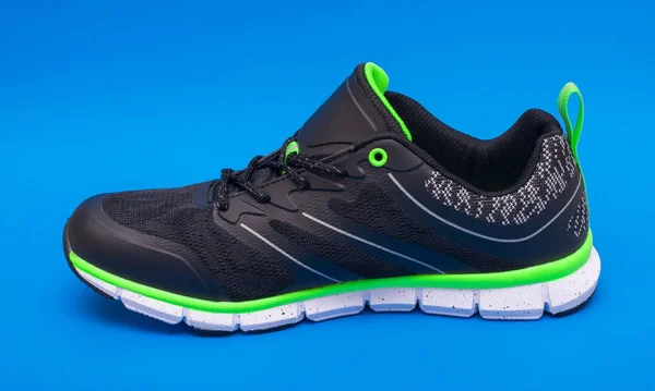 Limão verde e preto esporte unissex sapatos isolados no fundo azul . — Fotografia de Stock