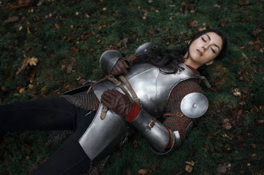 CHAINMAIL ve gizemli bir ormandaki yerde yatan zırhı giyen bir güzel savaşçı kız.