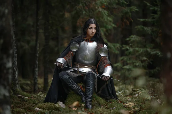 Egy gyönyörű harcos lány kard viselő chainmail és páncél egy titokzatos erdő. — Stock Fotó