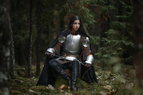 Gizemli bir ormanda CHAINMAIL ve zırh giyen bir kılıç ile bir güzel savaşçı kız.
