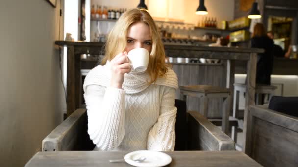 Ung vacker kvinna är leende i café och njuter doften av kaffe. — Stockvideo