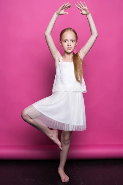 美丽的红头发的小女孩穿白色连衣裙，像粉红色背景模型构成. — 图库照片