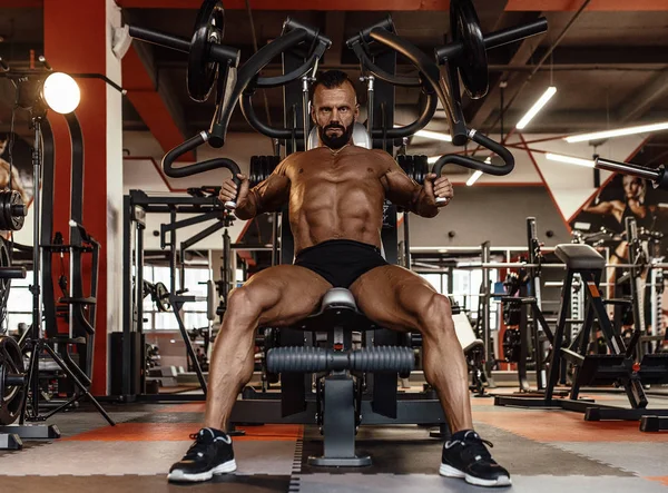 Hombre guapo con grandes músculos ejercitándose en el gimnasio. Muscular culturista haciendo ejercicios . — Foto de Stock