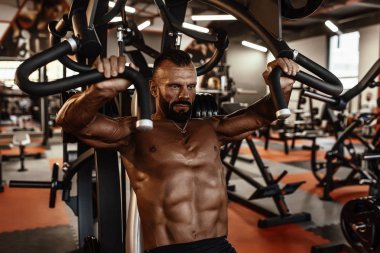 Yakışıklı adam büyük kas spor salonunda çalışma dışarı ile. Kaslı vücut egzersizleri yapıyor.