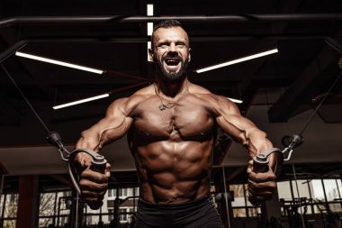 Yakışıklı adam büyük kas spor salonunda çalışma dışarı ile. Kaslı vücut egzersizleri yapıyor.