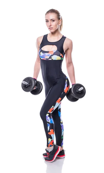 Sexy athletic young woman with perfect strong muscular body wearing sportswear tracksuit pumping up muscles with dumbbells isolated on white background. — Stock Photo, Image