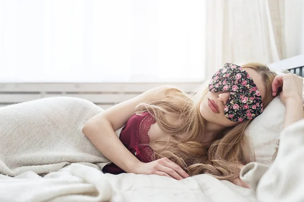 Hermosa joven que duerme en su cama en casa con la máscara de ojos vendados . — Foto de Stock