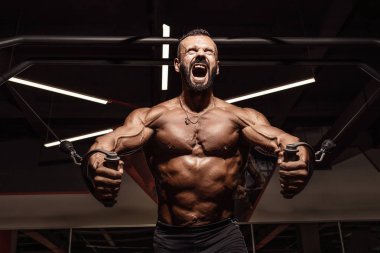 Yakışıklı adam büyük kas spor salonunda çalışma dışarı ile. Kaslı vücut egzersizleri yapıyor.