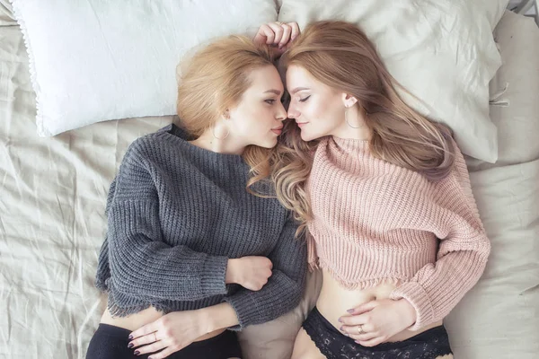 Two young women in a bright bedroom lying in bed. Sensual loving couple. — Stock Photo, Image