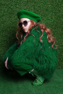 Yeşil elbise giyen sevimli küçük Kızıl saçlı kız moda studio portresi.