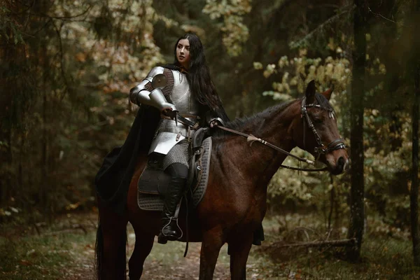 一个美丽的战士女孩用剑穿着锁链和盔甲骑在一个神秘的森林马 — 图库照片