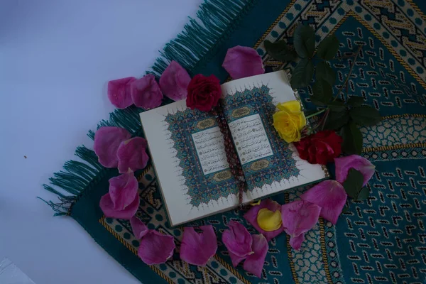 Коран с четками и цветами изолированы на белом фоне — стоковое фото