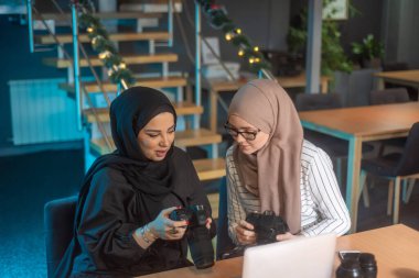 Dizüstü bilgisayarında yazı yazan genç Müslüman öğrenciler, ellerinde fotoğraf makineleri ve fotoğrafçılık hakkında bilgi ediniyorlar.