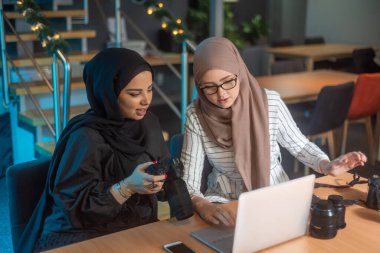 Dizüstü bilgisayarında yazı yazan genç Müslüman öğrenciler, ellerinde fotoğraf makineleri ve fotoğrafçılık hakkında bilgi ediniyorlar.
