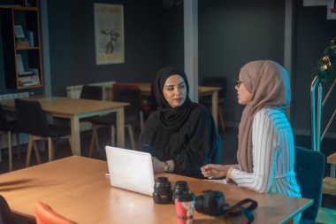 Dizüstü bilgisayarında yazı yazan genç Müslüman öğrenciler, ellerinde fotoğraf makineleri ve fotoğrafçılık hakkında bilgi ediniyorlar.