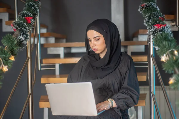 Beautiful girl with hijab typing on laptop, speak on phone and learning about photography