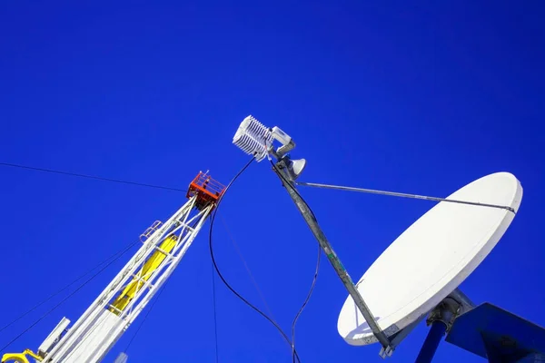 Antena parabólica no fundo do céu azul e plataforma de óleo . — Fotografia de Stock