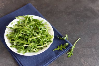 Siyah masada beyaz seramik kasede taze yeşil roka..