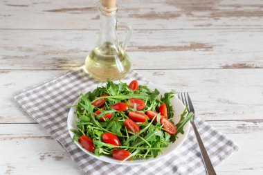 Taze yeşil roka salatası ve beyaz seramik kasede domates kirazı..