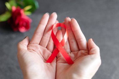 1 Aralık 'ta dünya yardımlarının sembolü olarak kırmızı kurdele tutan kadın, kampanyada Hiv' le yaşayan insanlara yardım ediyor.