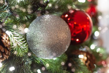 Noel ağacı süslemesi. Kırmızı ve gümüş toplar ve ışıklı çelenkler. Bokeh 'le yeni yıl fotoğrafı. Kış tatili hafif dekorasyonu.
