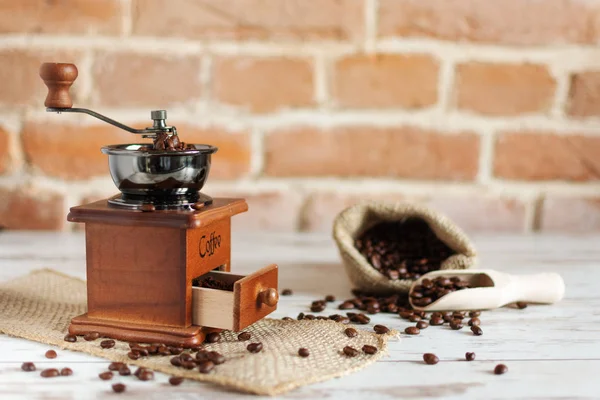 Ręczna szlifierka do kawy vintage i ziarna kawy w worku jutowym na drewnianym stole. — Zdjęcie stockowe