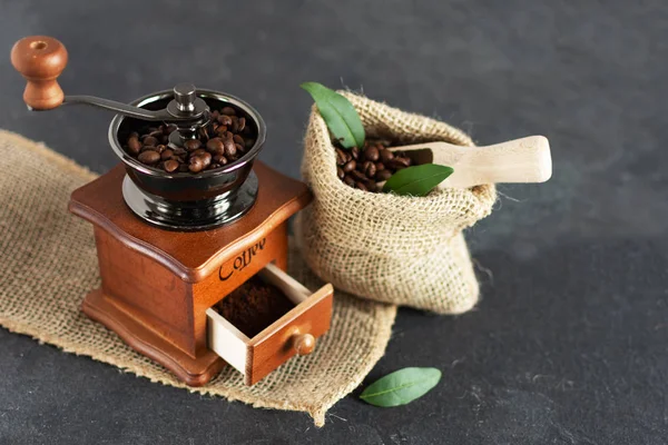 Ручная ручная кофемолка и кофейные зерна в мешочке из мешочка на деревянном столе . — стоковое фото